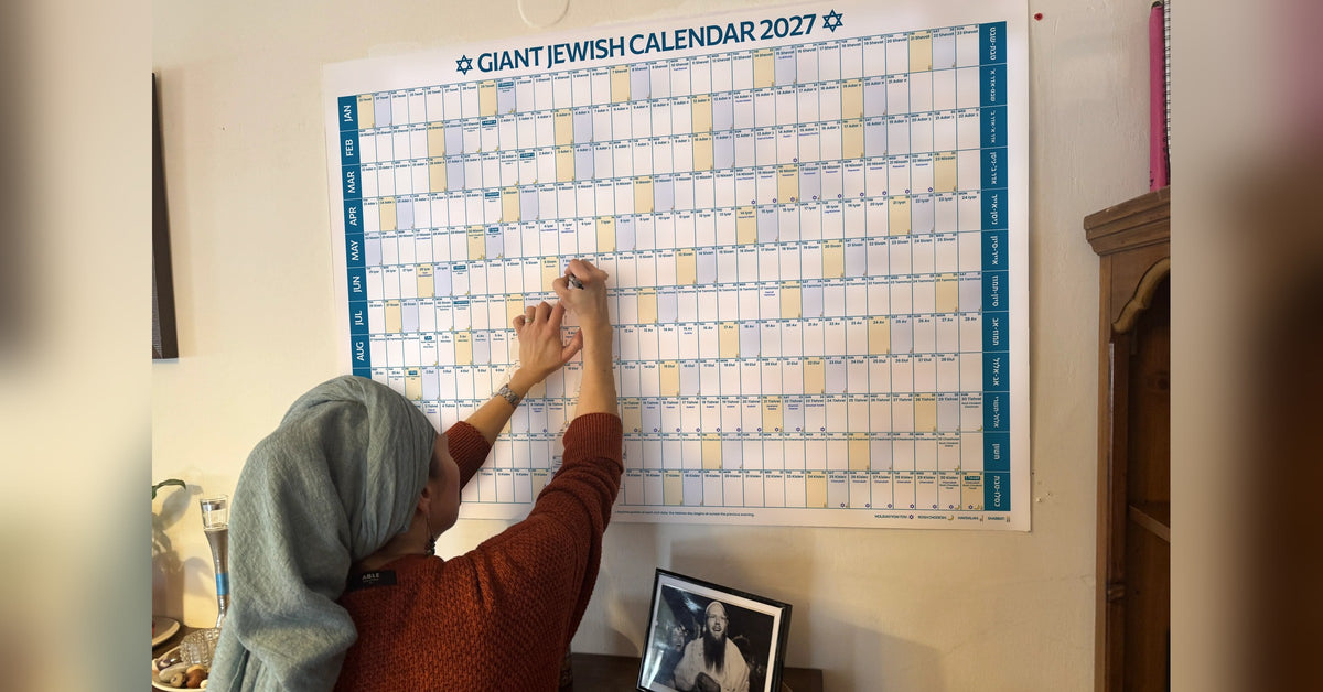 A woman writing plans on the Giant Jewish Calendar 2027 wall calendar